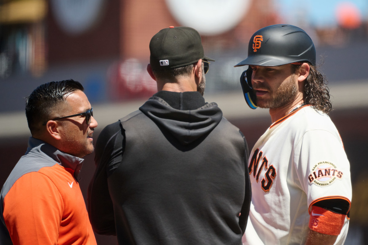 SF Giants infielder Brandon Crawford talks to manager Gabe Kapler and an athletic trainer during a stoppage of play in the sixth inning at Oracle Park on July 8, 2023.